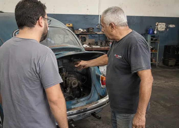 mecânico avaliando acionamento de embreagem em carro antigo